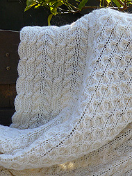 naturweisse, gestrickte Wolldecke im Aran-Muster